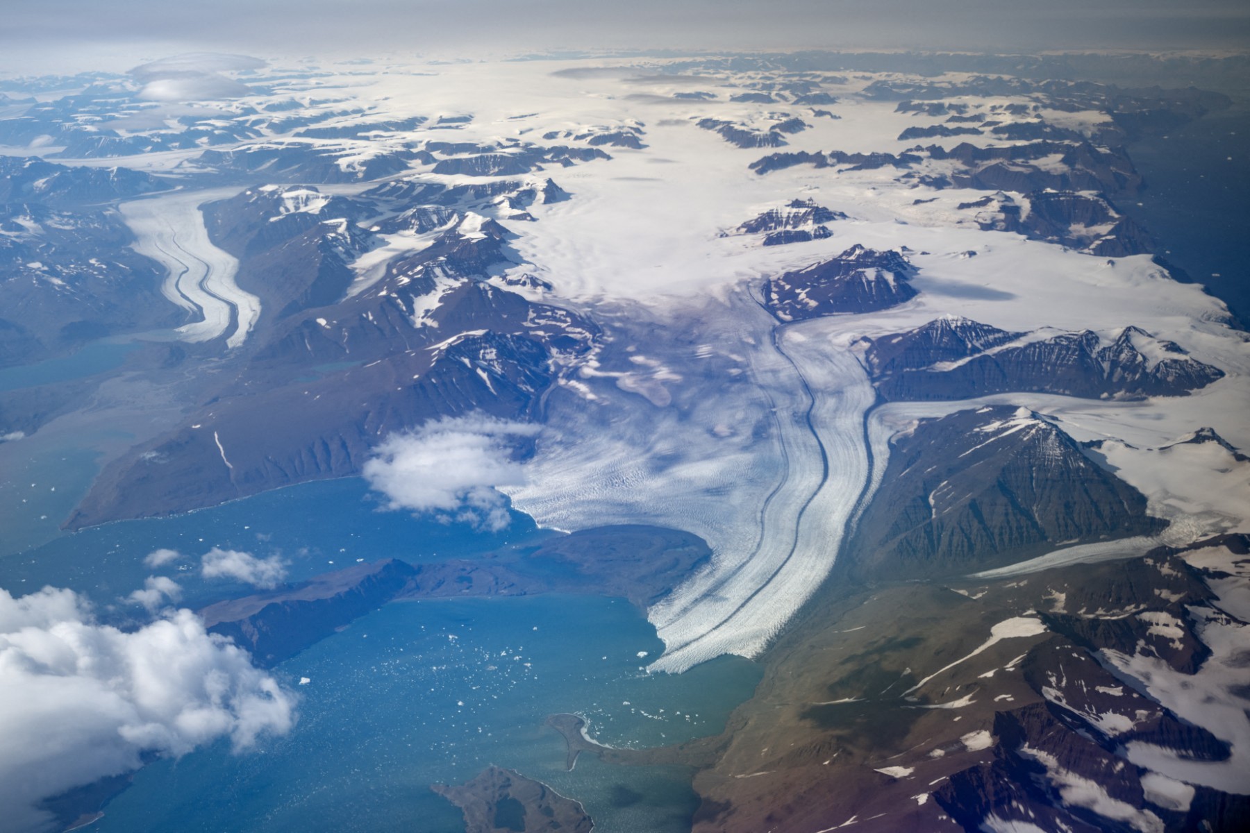 This aerial photograph taken on August 21, 2023, shows a range half melted glaciers in Scoresby Fjord near Ittoqqortoormiit, Greenland. The French National Centre for Scientific Research (CNRS) is undertaking an expedition to explore Greenland's isolated fjords, the planet's largest fjord system, which remains vastly understudied. The expedition, arranged by the volunteer-run French initiative Greenlandia, is dedicated to understanding the climate change's effects on Scoresby Fjord and its inhabitants. (Photo by Olivier MORIN / AFP)
